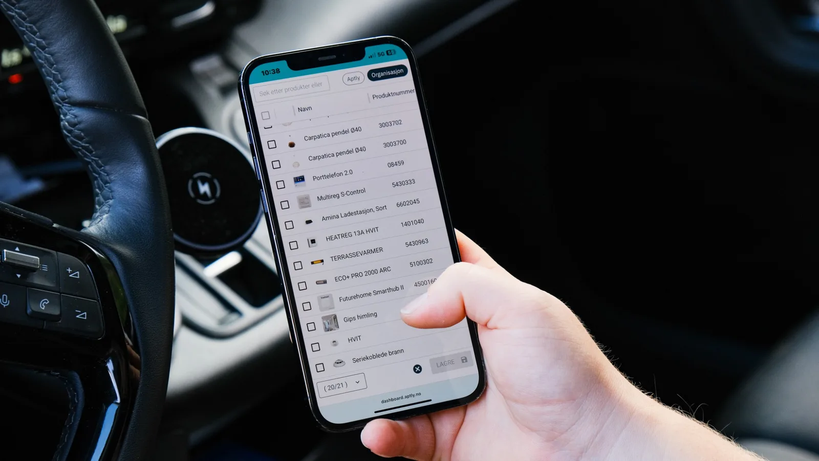 Håndverker i bilen blar i produktlisten i Aptly på mobilen